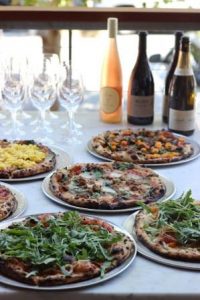 Photo of several pizzas and bottles of wine