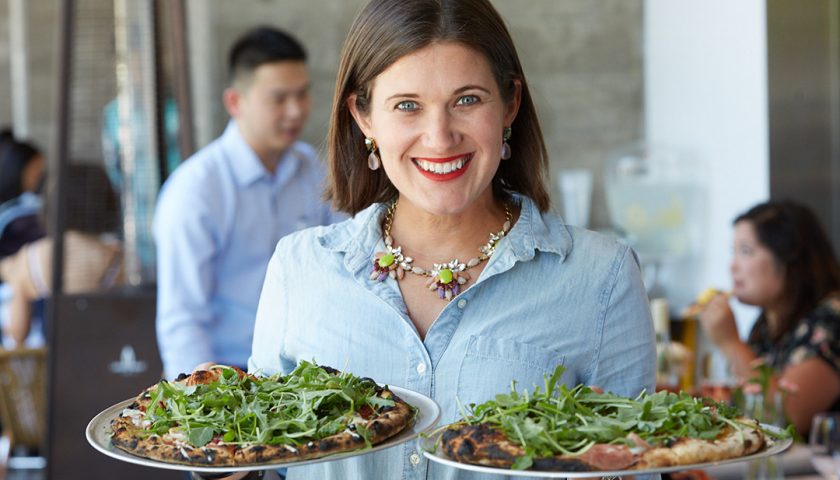 Photo of a server holding two pizzas