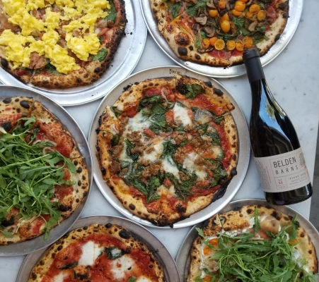 Photo of several pizzas and a bottle of red wine